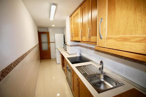 una cocina con fregadero y armarios de madera en Apartamento Postiguet, en Alicante