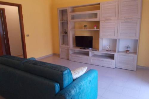 ein Wohnzimmer mit einem blauen Sofa und einem TV in der Unterkunft Sea Star - appartamento per le tue vacanze al mare in Riposto