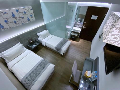 a small room with two beds and a mirror at Bliss Hotel Singapore in Singapore