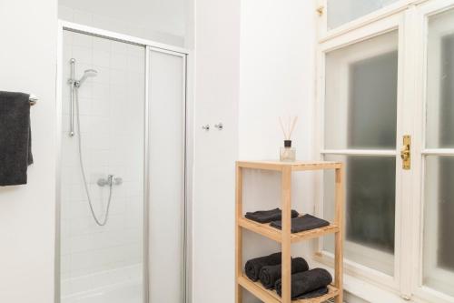 baño con ducha y estante de madera con toallas en The Ring Suites en Graz