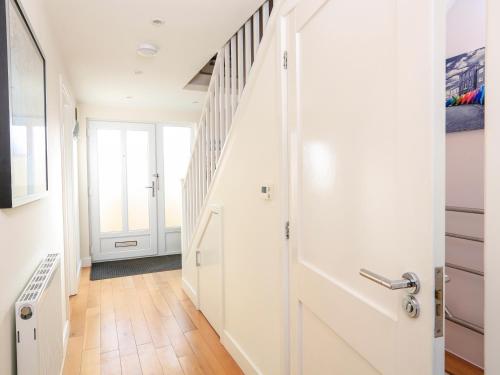 a hallway with a white door and a staircase at 2 The Bay in Kingsbridge