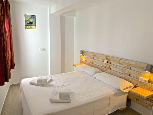 1 dormitorio con cama blanca y cabecero de madera en Apartamento Benidorm II, en Benidorm