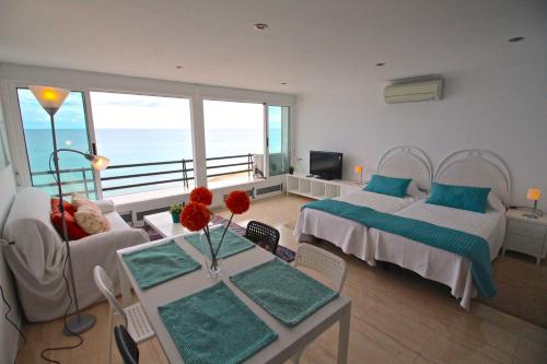 BenimagrellにあるLoft Playa Muchavistaのリビングルーム(ベッド2台、花のテーブル付)