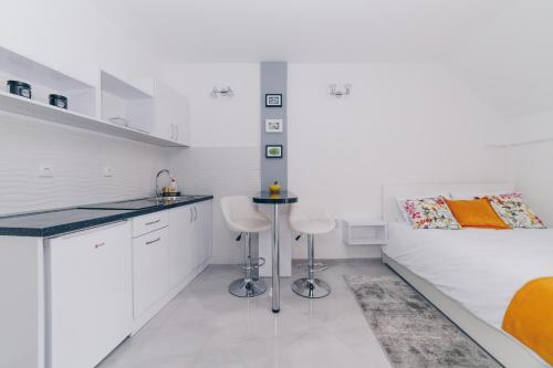 uma cozinha branca com dois bancos e uma cama em Duga apartmani em Kragujevac