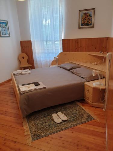 ein Schlafzimmer mit einem großen Bett und Hausschuhen auf dem Boden in der Unterkunft Bed & Breakfast LA BETULLA in Baselga di Pinè