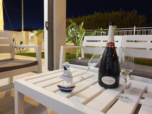 a bottle of wine and two glasses on a table at La Baia Apartments in Torre Lapillo