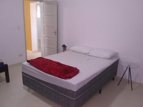 Un dormitorio con una cama con una manta roja. en Apartamento à 50 metros da praia - Itanhaém en Itanhaém