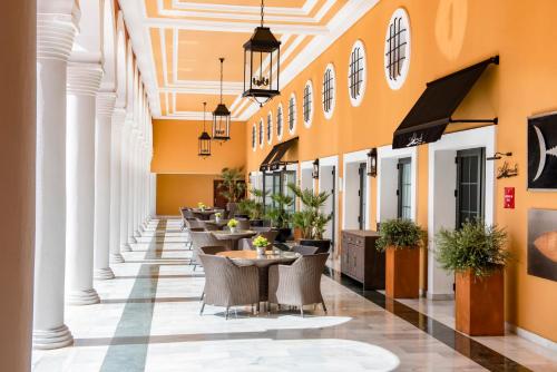 a restaurant with tables and chairs in a building at Palacio de Sancti Petri, a Gran Meliá - The Leading Hotels of the World in Chiclana de la Frontera