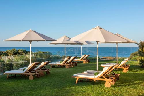 a group of lounge chairs and umbrellas on the grass at Palacio de Sancti Petri, a Gran Meliá - The Leading Hotels of the World in Chiclana de la Frontera