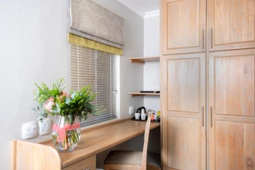 a kitchen with a wooden desk with a vase of flowers at Palm Park Hotel in Ellisras