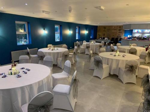 a dining room with white tables and chairs at Crown at Worthington Hotel in Standish