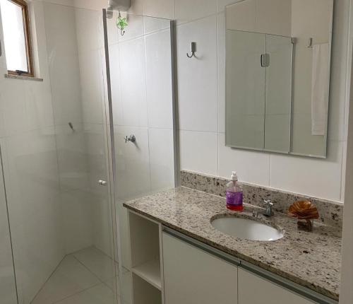 a bathroom with a shower and a sink and a mirror at Village em Imbassaí in Imbassai