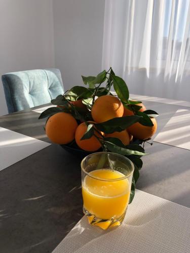 un vaso de zumo de naranja junto a un tazón de naranjas en Casa Doce, en Olhão