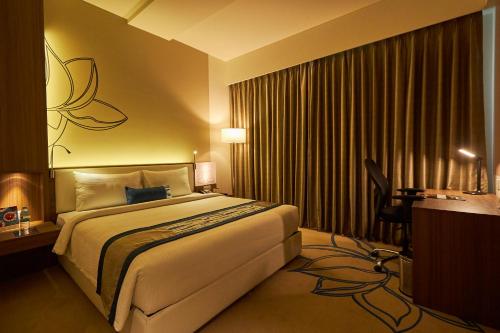 a hotel room with a large bed and a desk at Mercure Chennai Sriperumbudur in Sriperumbudur