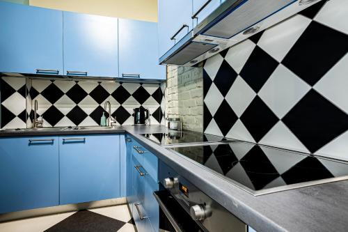 a kitchen with blue cabinets and black and white tiles at Blue Bird Hostel in Riga Old Town in Rīga