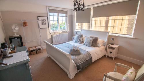 um quarto com uma grande cama branca e 2 janelas em Red Cottage B&B em Rye