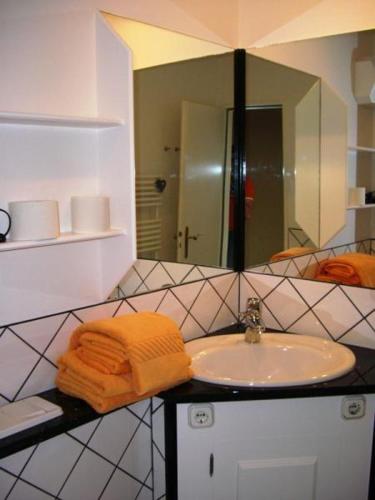 ein Badezimmer mit einem Waschbecken, einem Spiegel und Handtüchern in der Unterkunft Karl Theo Am Wald in Westerland