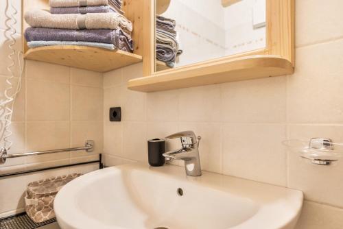 La salle de bains est pourvue d'un lavabo, d'un miroir et de serviettes. dans l'établissement Appartamento Adamello 14, à Pinzolo