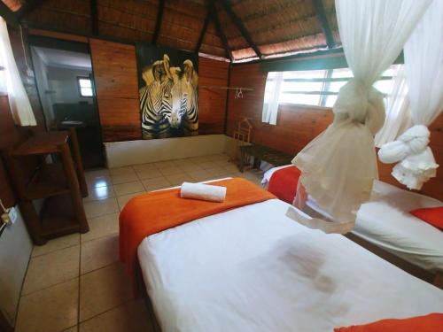 a room with two beds and a zebra painting on the wall at Pumusa Bushcamp in Hluhluwe
