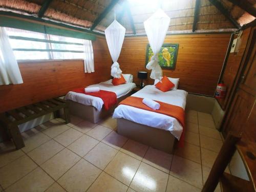 a bedroom with two beds and a bench in it at Pumusa Bushcamp in Hluhluwe