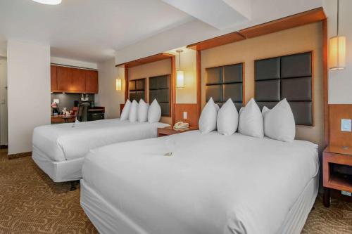 ein Hotelzimmer mit 2 weißen Betten und einer Küche in der Unterkunft Hotel Penticton, Ascend Hotel Collection in Penticton