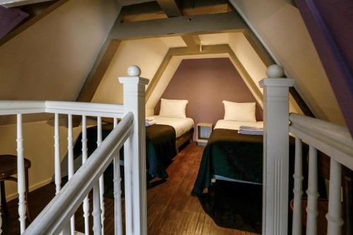 a attic room with two beds and a staircase at City Hotel Amsterdam in Amsterdam