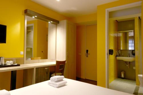 a bathroom with yellow walls and a sink and a mirror at City Hotel Amsterdam in Amsterdam