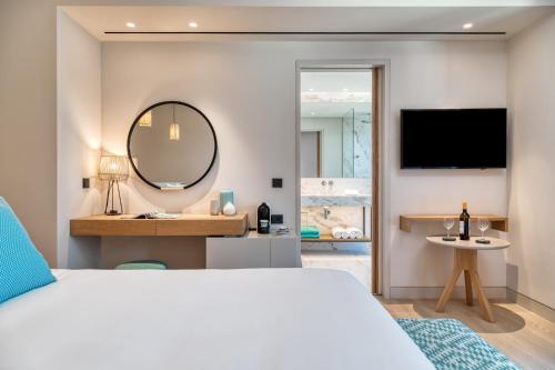 a bedroom with a large bed and a mirror at Vathi Cove Luxury Resort & Spa in Chrysi Ammoudia