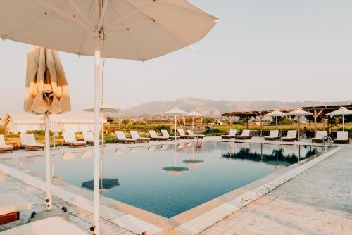 a swimming pool with umbrellas and lounge chairs at Sails on Kos Ecolux Tented Village in Marmari