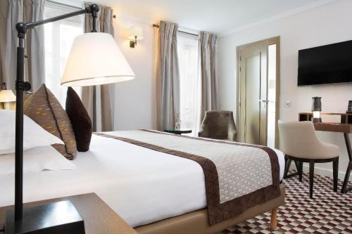 a hotel room with a bed and a desk at Hotel Phileas Lazare & Spa - Opera in Paris