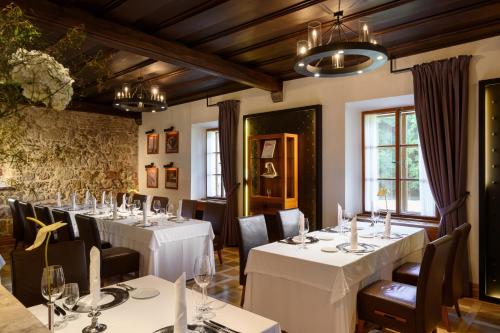 un comedor con mesas y sillas blancas en Hotel Grad Otočec - Relais Chateaux en Otočec