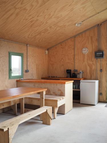 a kitchen with wooden tables and a refrigerator at Les Refuges de Mer in Petit Port