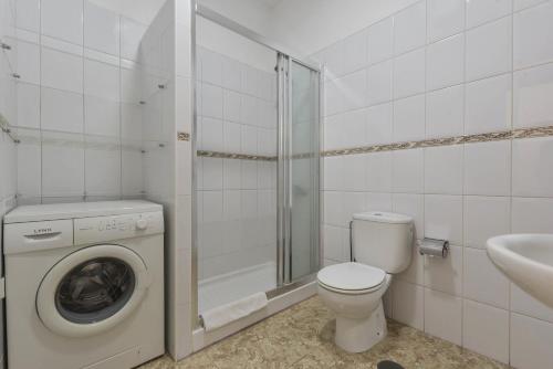 a bathroom with a toilet and a washing machine at Apartamento Bregador in Playa de San Juan