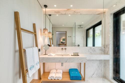 a bathroom with a sink and a large mirror at Vathi Cove Luxury Resort & Spa in Chrysi Ammoudia