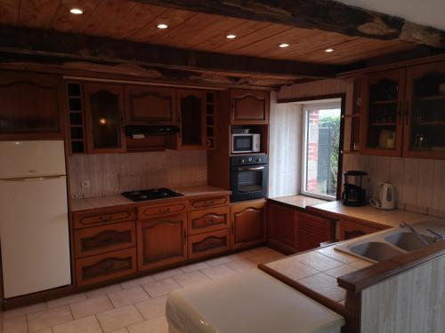 a large kitchen with wooden cabinets and a window at Nid douillet en Foret de Broceliande in Ploërmel