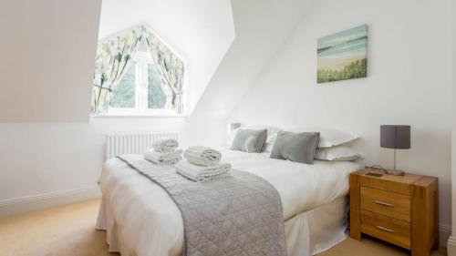 een witte slaapkamer met een bed met handdoeken erop bij Daintree - Bournemouth in Bournemouth