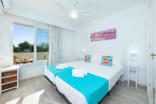 a white bedroom with a bed and a window at Apartamento Villa Cancun in Port d'Alcudia