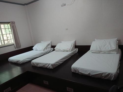 three beds in a room with white sheets and pillows at Jinguang Homestay in Fanlu