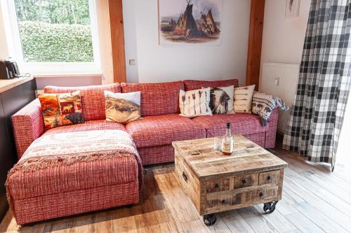 a living room with a red couch and a coffee table at Ferienwohnung Wild West in Eging