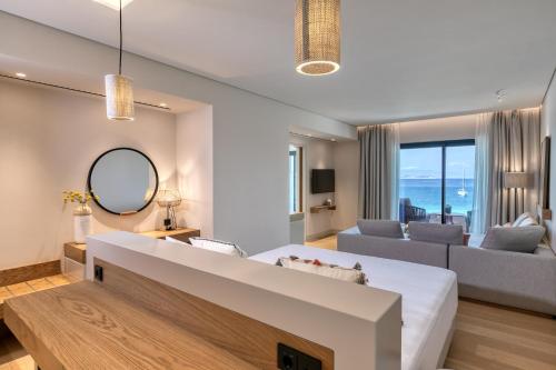 a living room with a large couch and a large window at Vathi Cove Luxury Resort & Spa in Chrysi Ammoudia