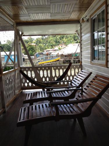a wooden bench on a porch with a hammock at Hotel Caribbean View in Bastimentos