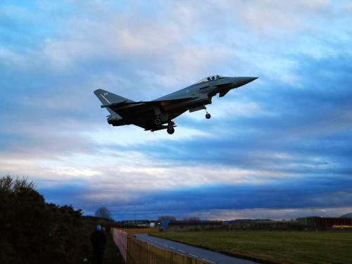 a fighter jet is flying over a fence at Lossiemouth House in Lossiemouth