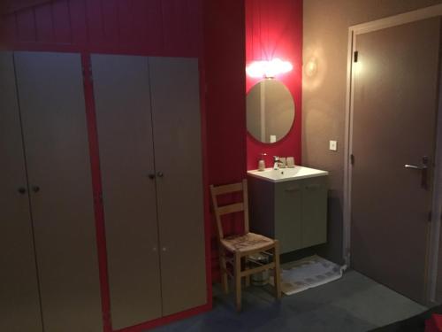 a bathroom with a sink and a mirror and a chair at Hôtel et Appart'Hôtel Restaurant L'Adray in Longefoy