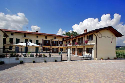 un grand bâtiment avec une clôture devant lui dans l'établissement Agriturismo Cascina Mariale, à Albiano dʼIvrea