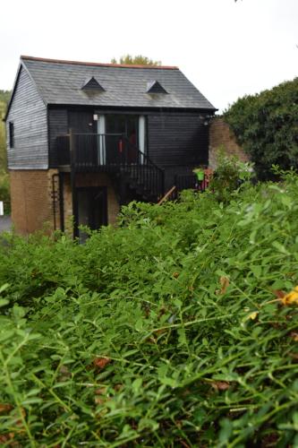 a house with a balcony and a bunch of bushes at Watercress Barns in Sittingbourne