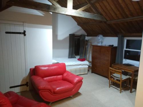 a living room with a red chair and a bedroom at Watercress Barns in Sittingbourne