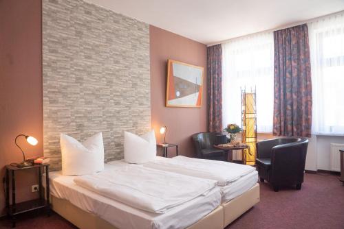 pokój hotelowy z dużym łóżkiem i 2 krzesłami w obiekcie Hotel Adagio w Lipsku