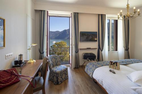 a hotel room with a bed and a desk and a window at International au Lac Historic Lakeside Hotel in Lugano