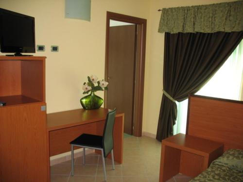 a hotel room with a desk with a vase of flowers at Da Santo Hotel Ristorante Pizzeria in Ferrara