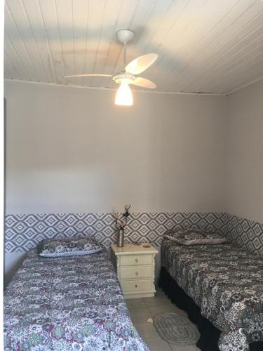 a bedroom with two beds and a ceiling fan at Quarto Paulínia 2 in Paulínia